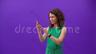 Curly女孩用一个紫色背景的<strong>新手机</strong>玩游戏
